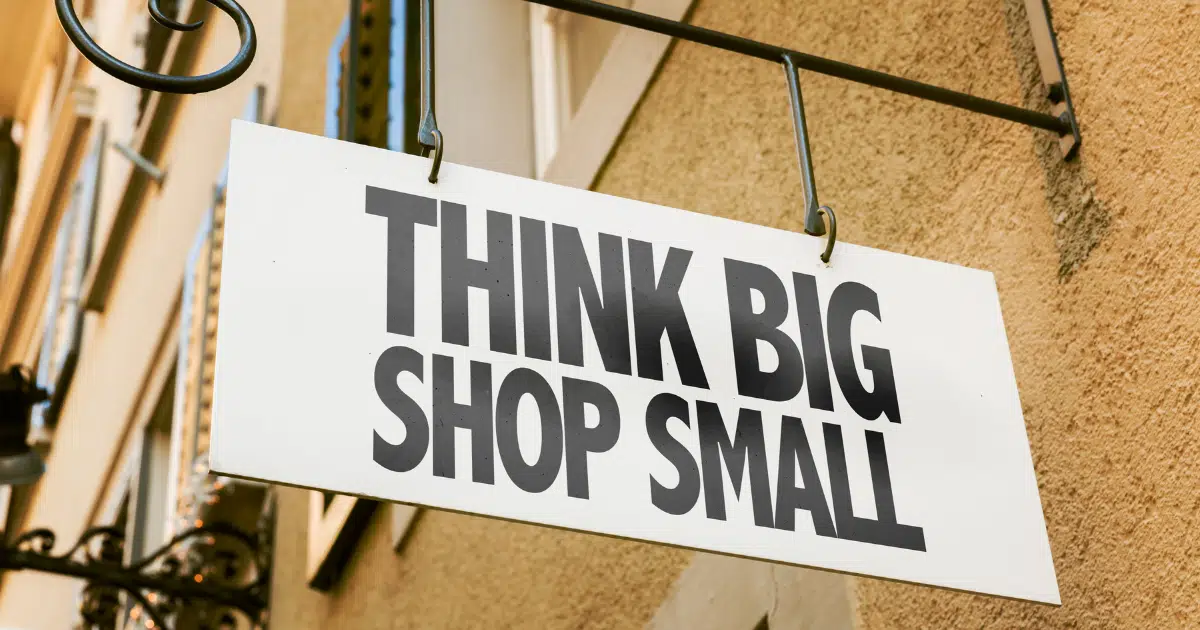 a sign reading 'think big shop small' hangs on an exterior wall 