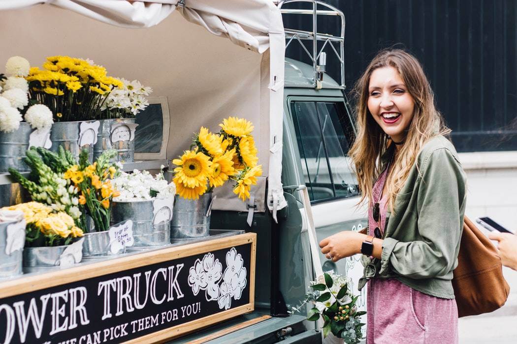 a retail salesperson laughs in front of a flower truck