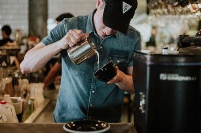 a barista pours a latte at a coffee shop
