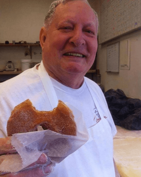 a Yum Yum Bakery employee holds a donut
