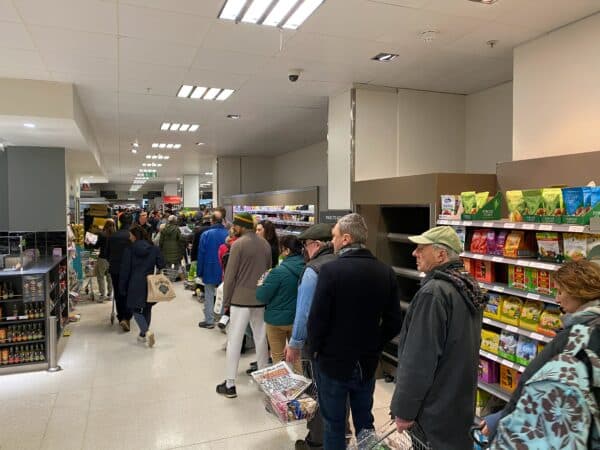 customers in a grocery store wait in a retail checkout line
