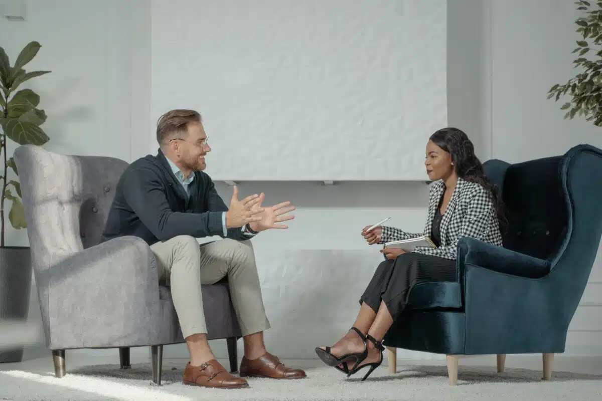 an employer performs a retail recruitment interview with a candidate while sitting on sofa chairs