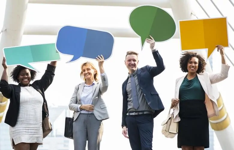 four smiling people hold up cardboard chat bubbles 