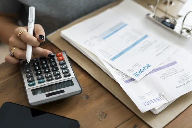 a retail accountant adds up invoices with a calculator