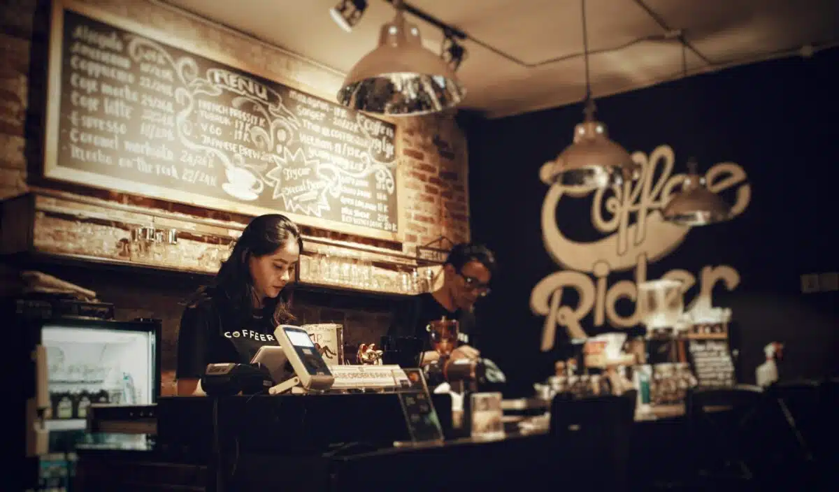 two baristas stand behind a counter at a coffee shop