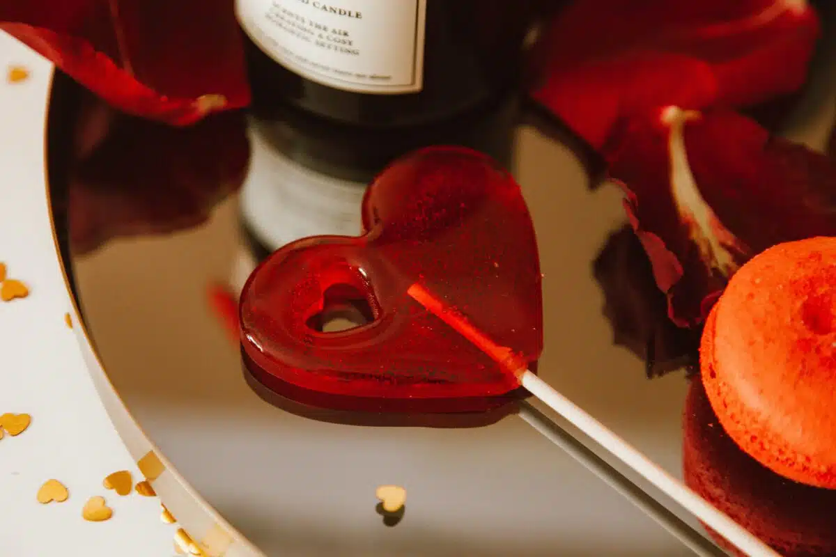 an up close view of a valentines day promotion with a red candy lollipop, a red macaroon, a candle, and red flowers