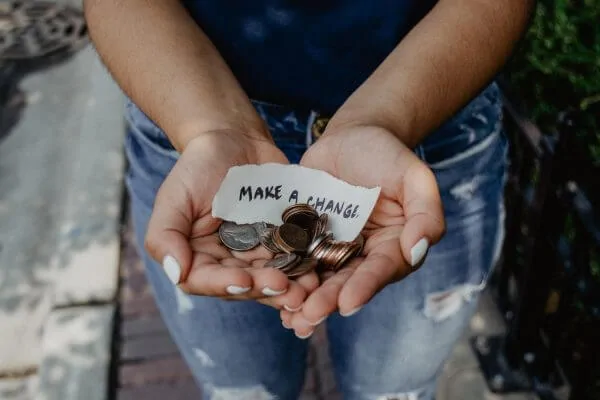 a person holds coins in their cupper hands with a piece of paper that reads 'make a change'