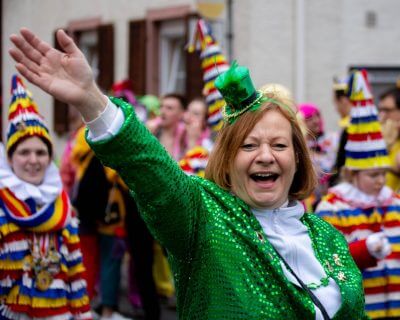Lady dressed in St. Paddy's Day outfit waving from a parage