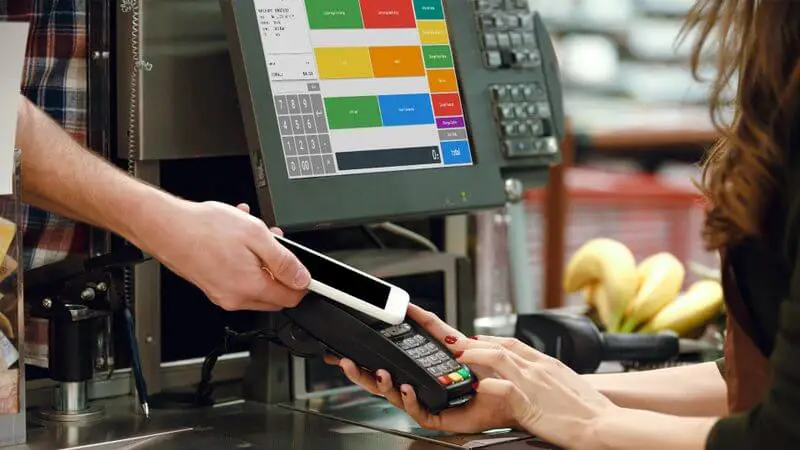 a convenience store customer pays with their phone at a POS system