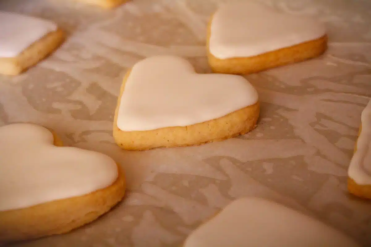 heart shaped cookies with white icing sit on wax paper