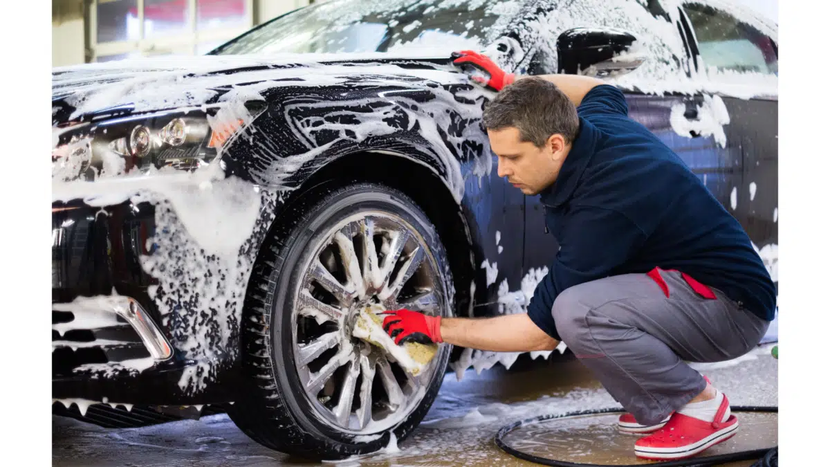 a car wash employee cleans the wheels of a car
