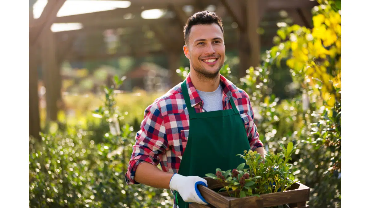 a person smiles as they walk through a gardening center holding a planter