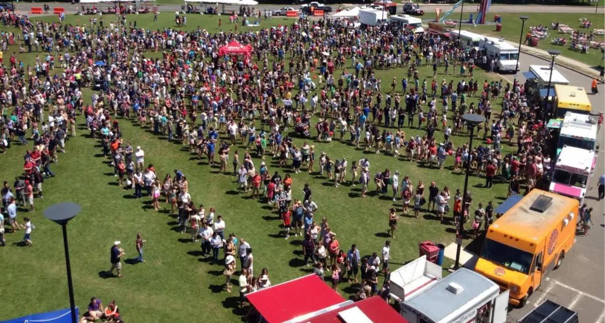 people wait in line for different food trucks at a festival