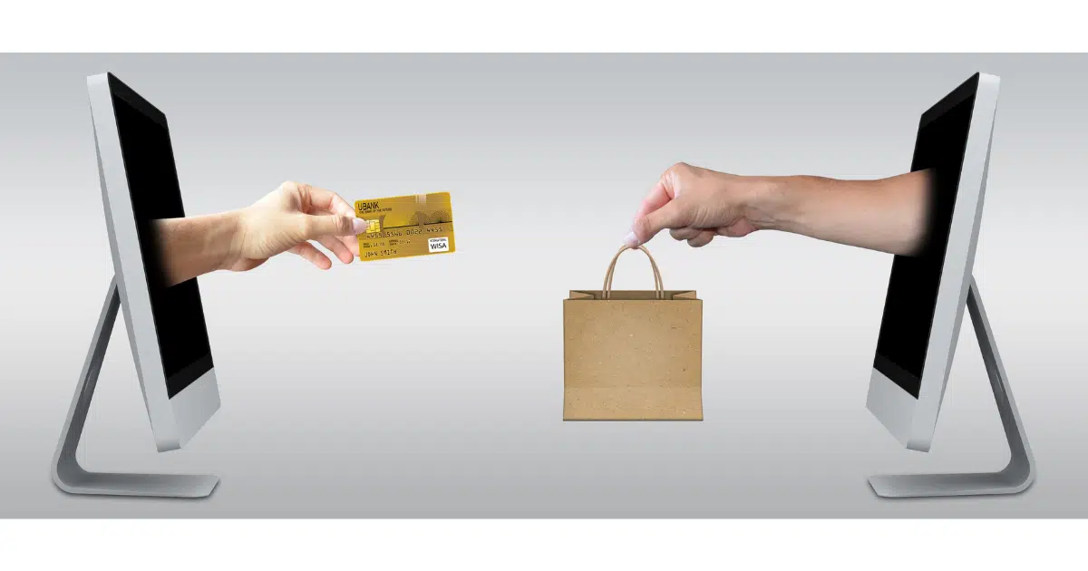 a stylized image with two people reaching their hands through computer screens, one with a credit card and the other with a shopping bag