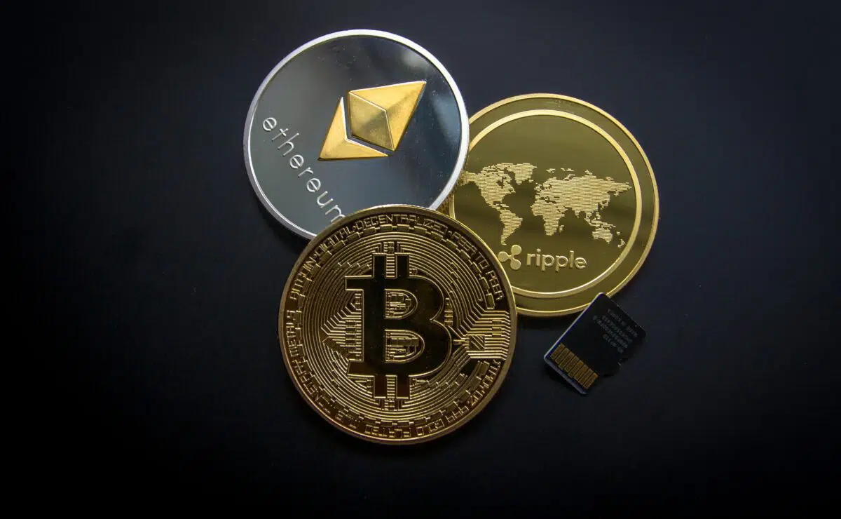 an illustration of three metal coins representing ethereum, Bitcoin, and ripple