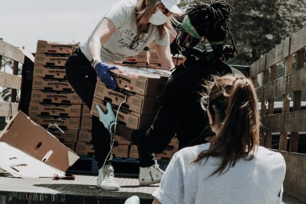 two volunteers help unload donated boxes off of the back of a truck