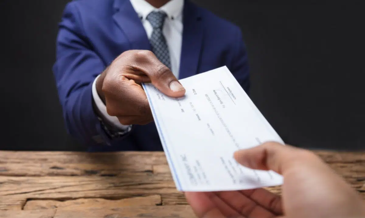 a payroll manager hands an employee a check