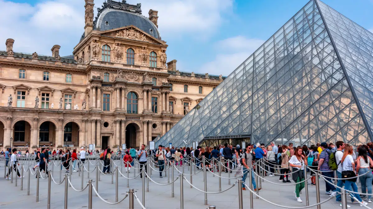 the exterior of The Louvre with visitors getting in line