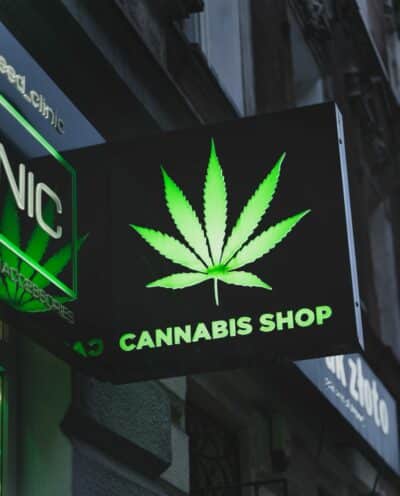 a green and black sign with marijuana leaf design that says cannabis shop