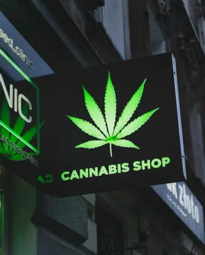 the exterior of a dispensary with a sign reading 'CANNABIS SHOP' and a marijuana leaf