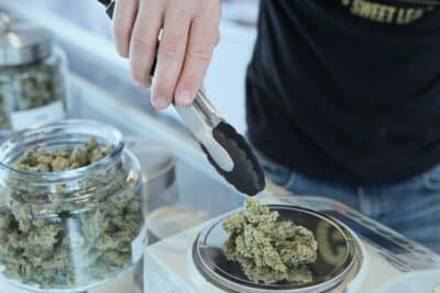 a budtender uses a scale to weigh marijuana flower at a cannabis dispensary