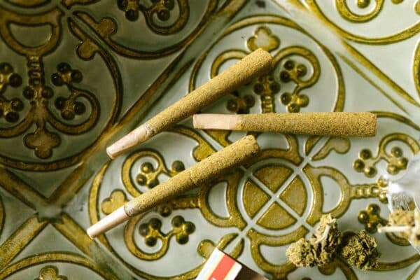 hash rolled joints and cannabis buds sit on top of a gold and white tile surface