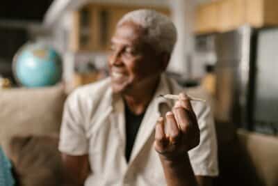 a dispensary customer smiles as he holds a cannabis joint