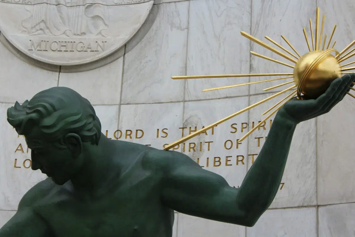 Statue holding a sun outside of the Michigan State Capitol building