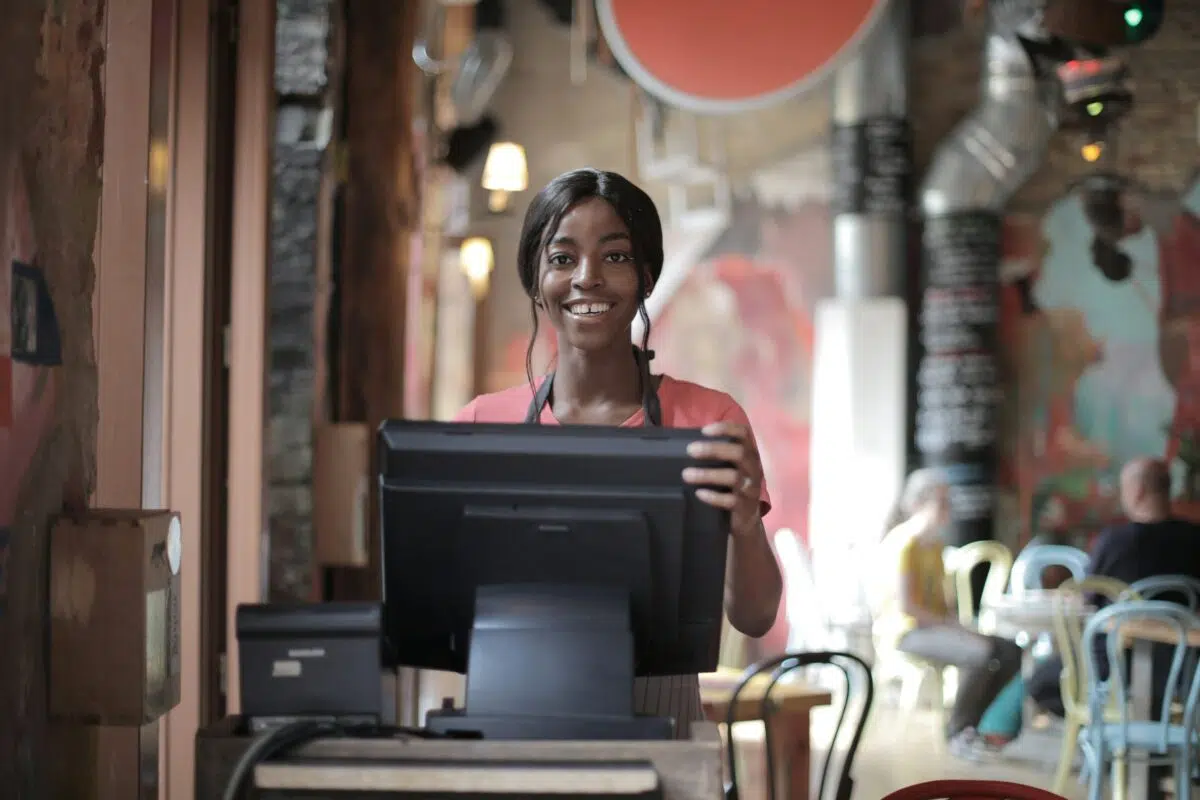 a cashier smiles while standing behind a retail POS system