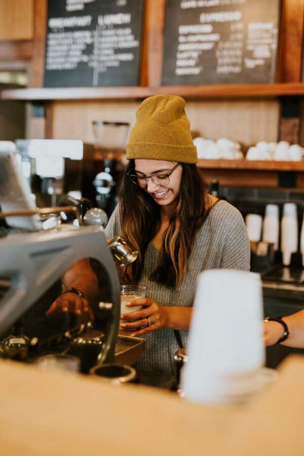 a photo showing a barista making an espresso drink and smiling