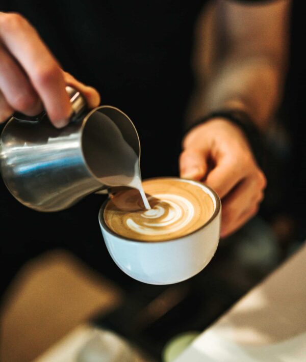 a photo of a barista pouring a latte in a coffee shop