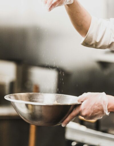 a baker throws salt into a mixing bowl