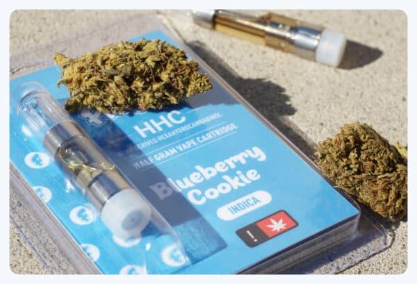 a photo showing an indica vape cartridge with some cannabis buds around it