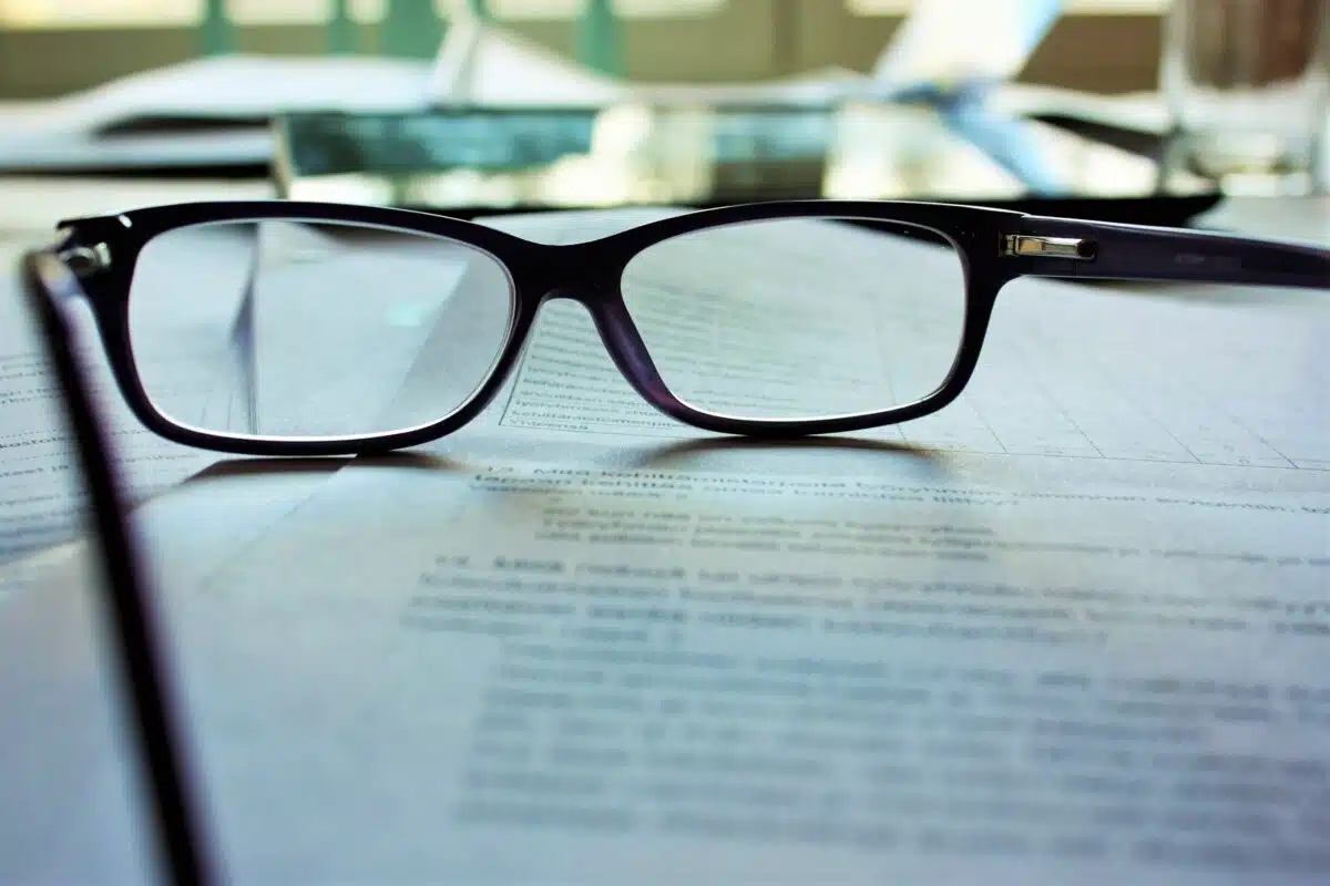 a pair of reading glasses sits on top of paperwork
