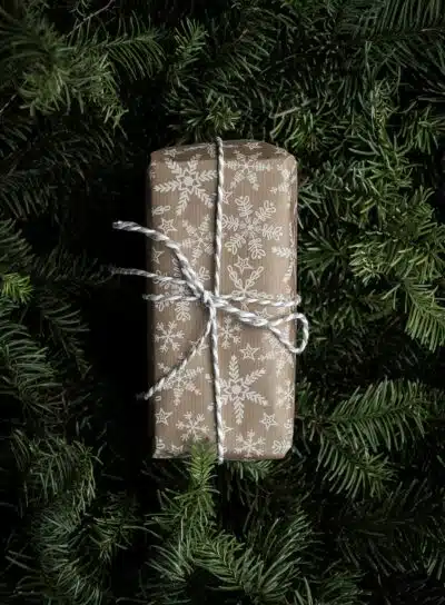 a holiday gift wrapped in snowflake wrapping paper sitting on wreathes