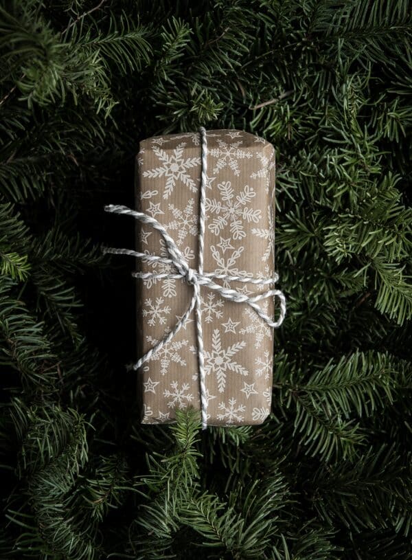 a photo of a holiday gift wrapped in paper sitting on top of wreathes