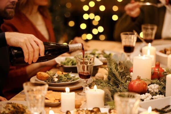 dinner guests pour wine at a table decorated for christmas