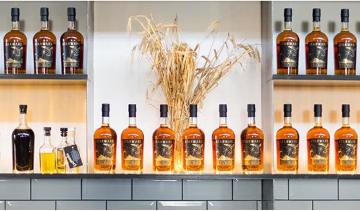 whiskey bottles sit on shelves behind a bar