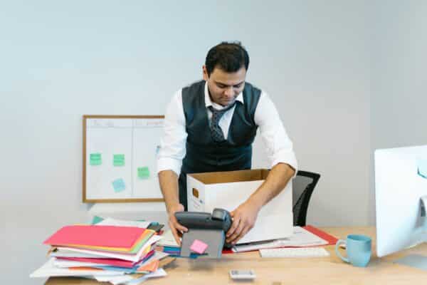 an office worker clears papers and clutter off their desk