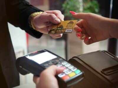 a retail cashier takes a customer credit card to process with a credit card reader