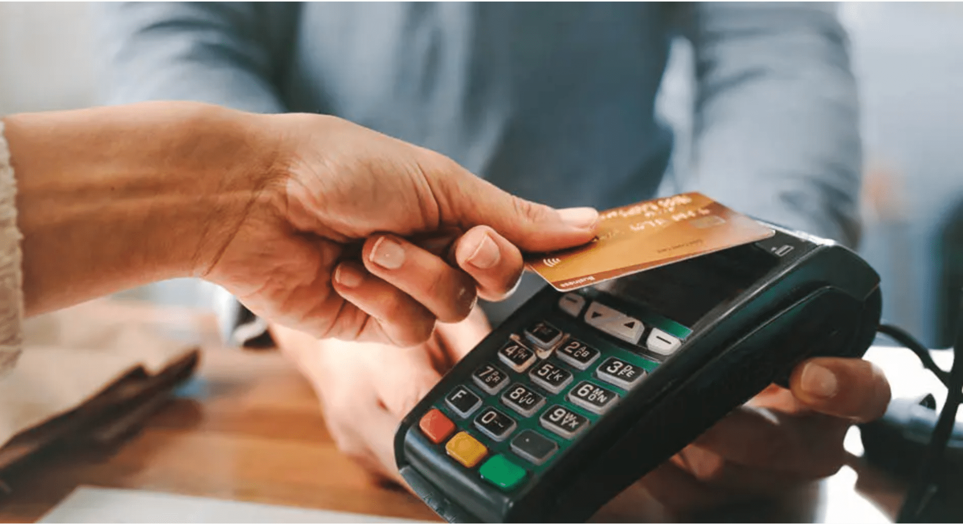 Person uses a credit card at a contactless payment terminal in a retail store