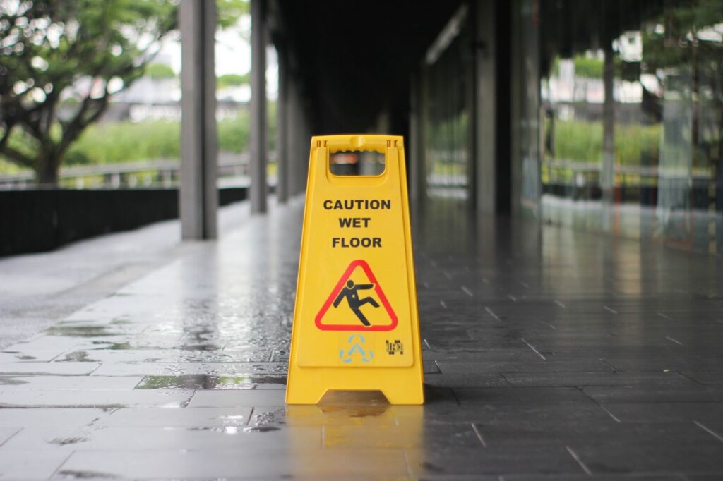 Yellow sign in a walkway at a store showing a man falling and the text "caution wet floor" written on it