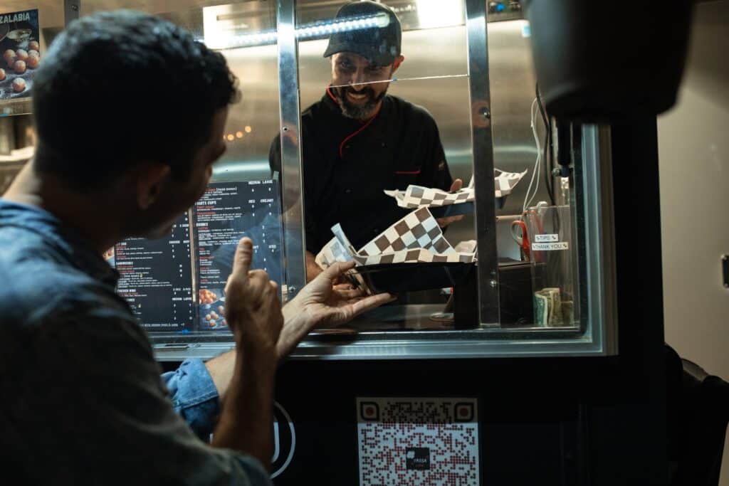 a quick serve food truck operator hands a customer food