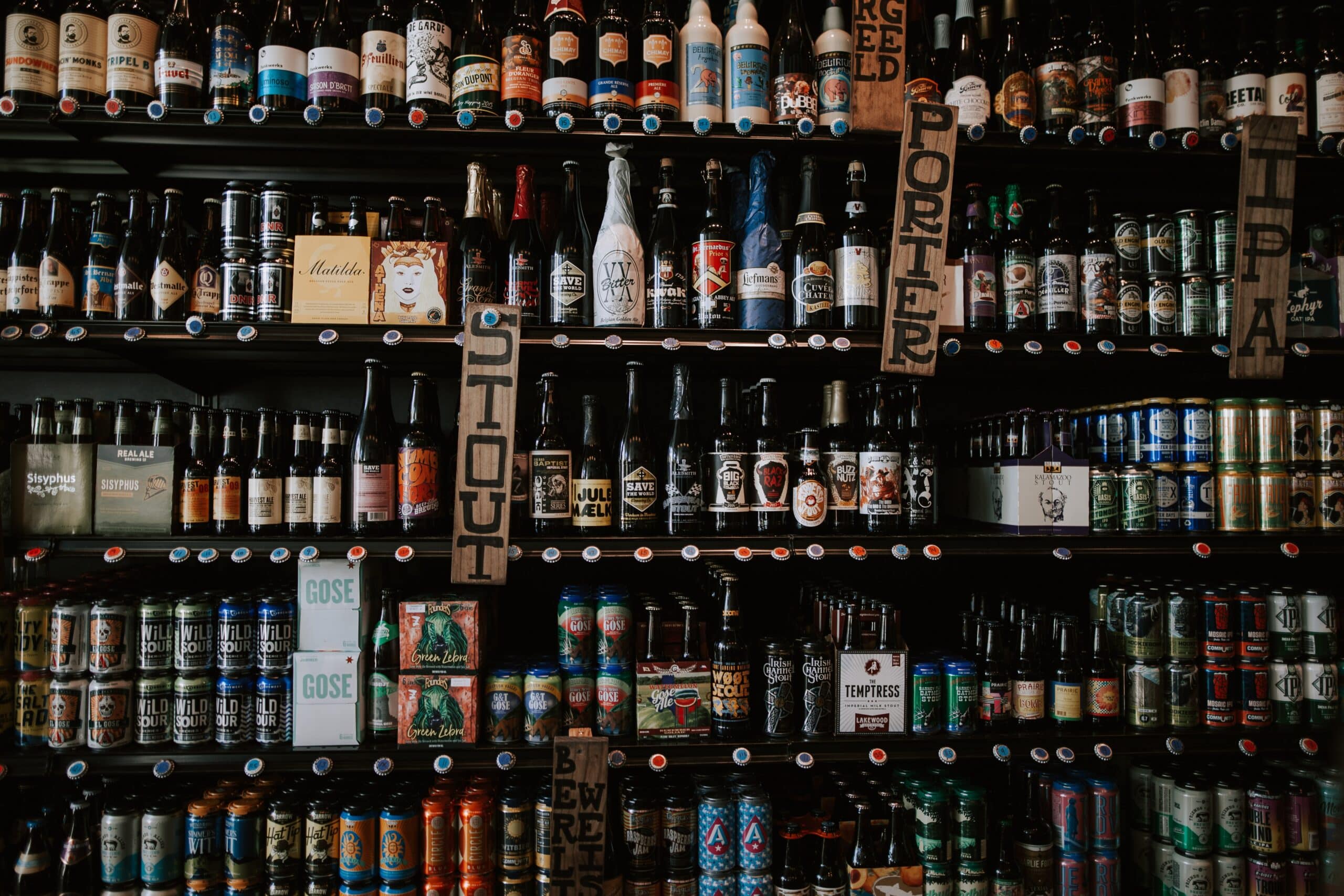 bottles of beer sit on display shelves at a convenience store 