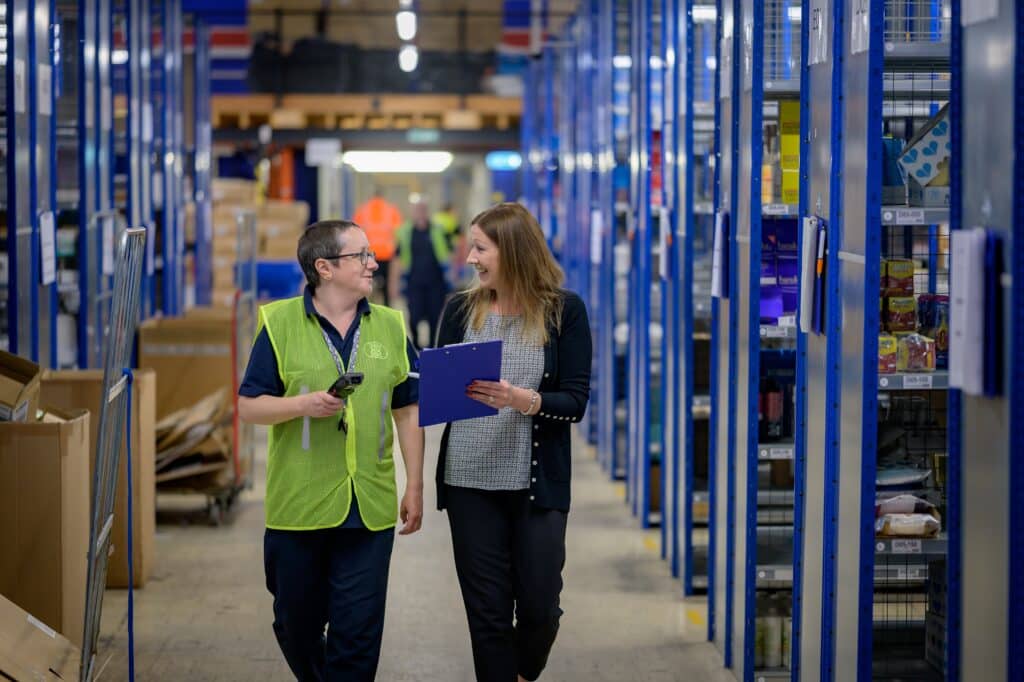 two retail associates walk through a warehouse after doing inventory reconciliation using a clipboard and mobile point of sale tool