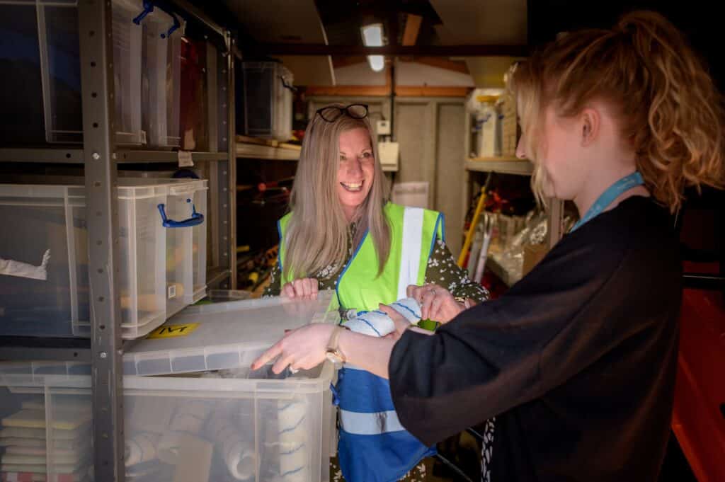 two retail workers look through bins in a storage while doing inventory reconciliation