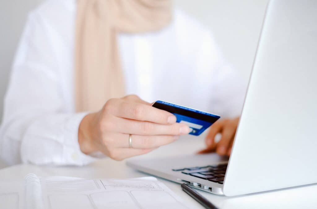 an eCommerce customer holds their credit card as they shop on their laptop