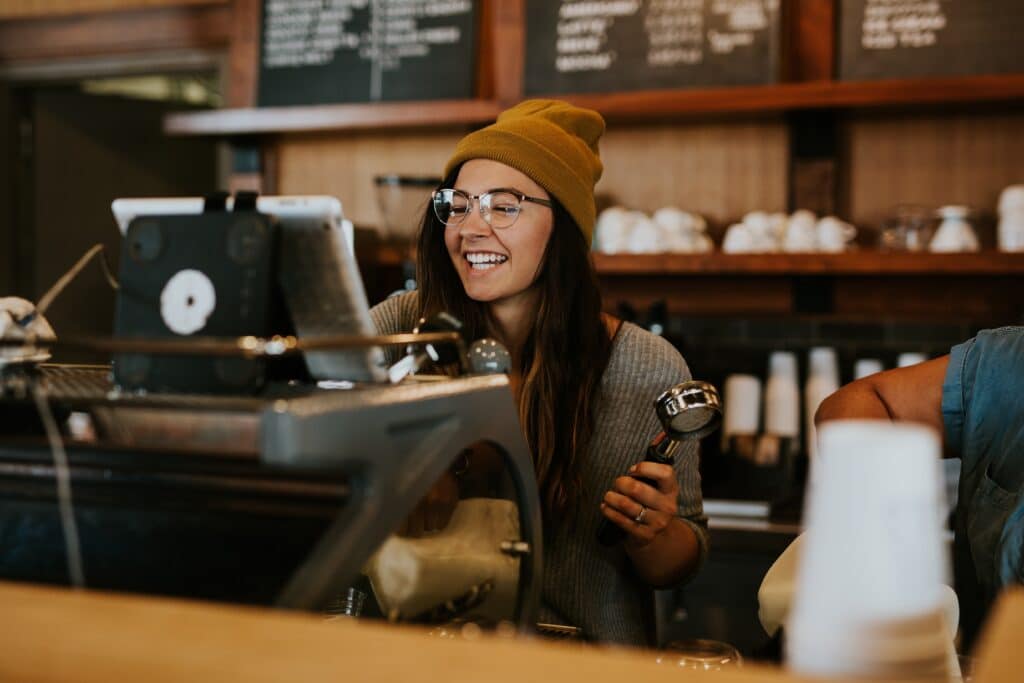 a barista smiles behind an espresso machine 