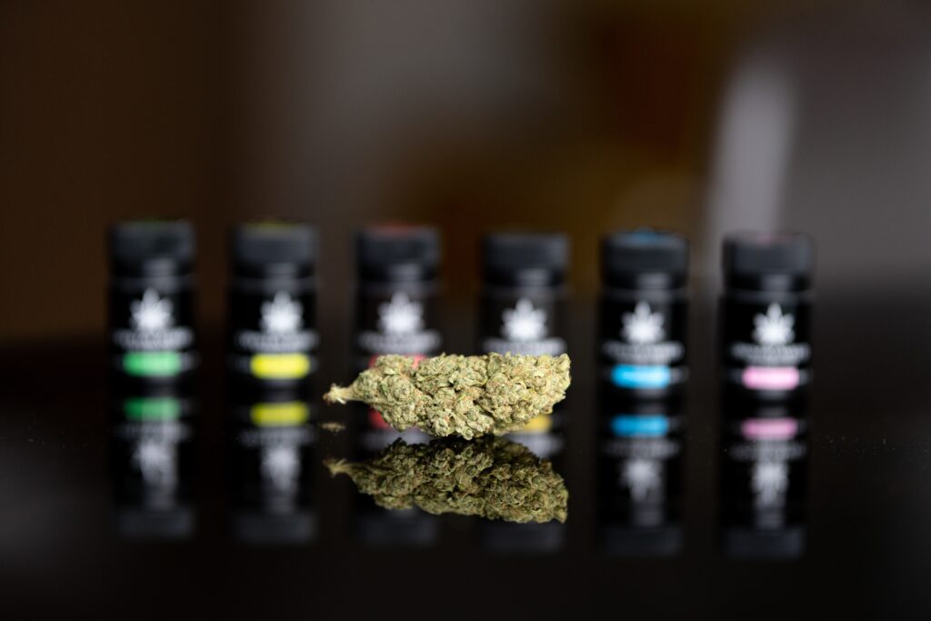 marijuana flower sits on a dispensary counter in front of other cannabis canisters