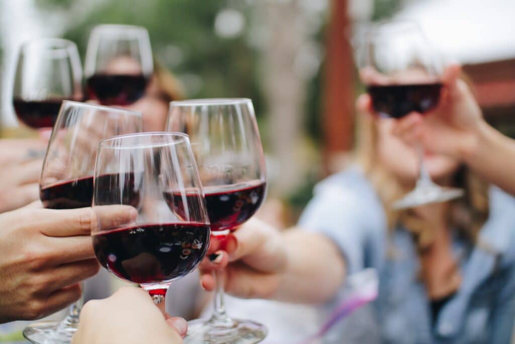 guests of a wine tasting event cheers each other with glasses of red wine